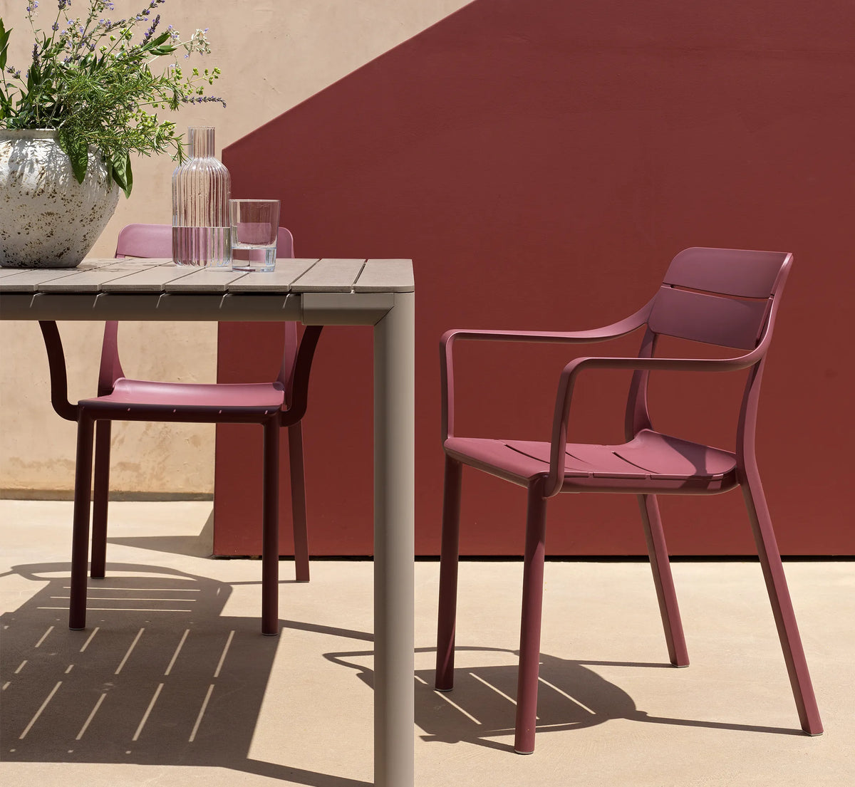 Conjunto de sillas CASSIA con brazos en una terraza.