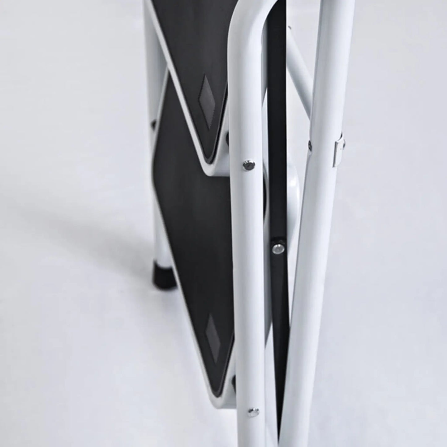 Taburete White plegado mostrando su diseño compacto para almacenamiento en espacios pequeños.