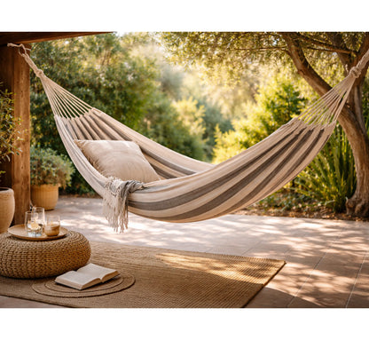 Hamaca BAHAMAS instalada en un porche de madera, creando un rincón de bienestar y lectura.