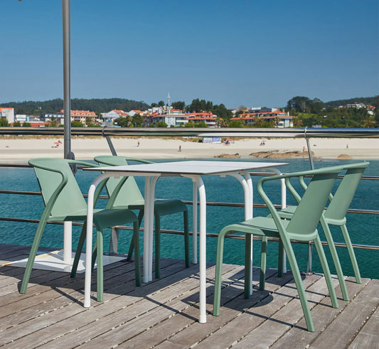 Mesa RODAS acompañada de sillas FADO, configurando un rincón de comedor exterior moderno, higiénico y sofisticado.