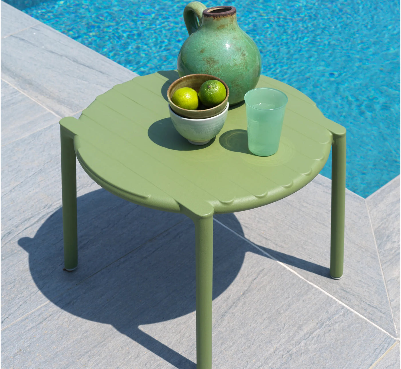Mesa baja DOGA de NARDI en color verde junto a la piscina.