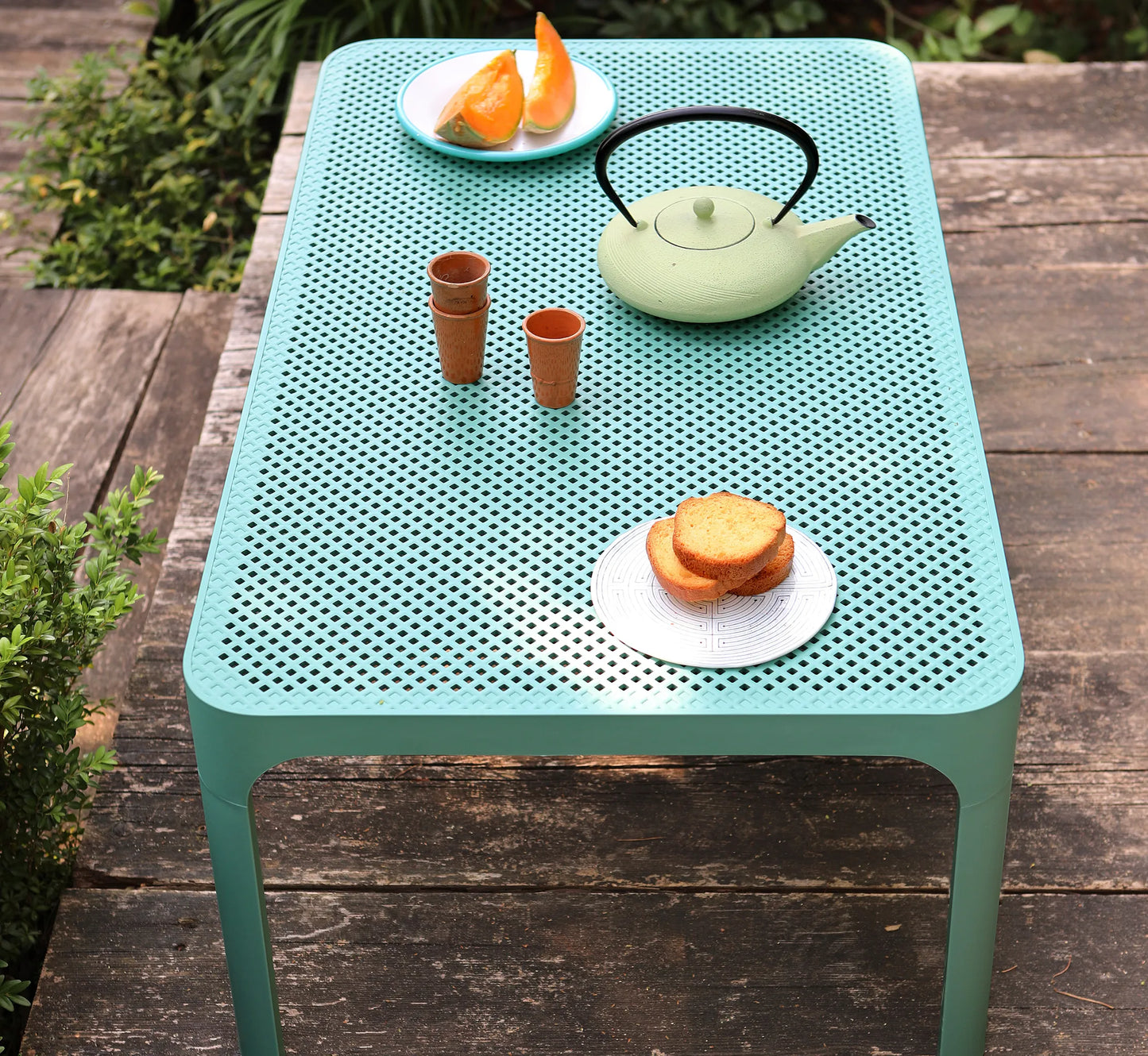 Mesa NET Rectangular vestida con detalles de diseño, invitando a una experiencia de bienestar y exclusividad en el jardín.