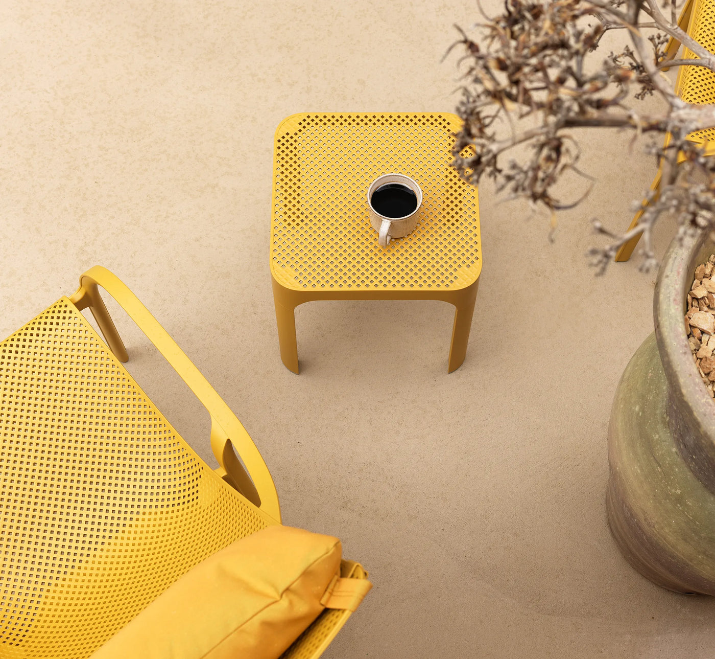 Detalle del icónico patrón perforado de la mesa NET de Nardi, donde la luz mediterránea crea juegos de sombras elegantes y sugerentes.