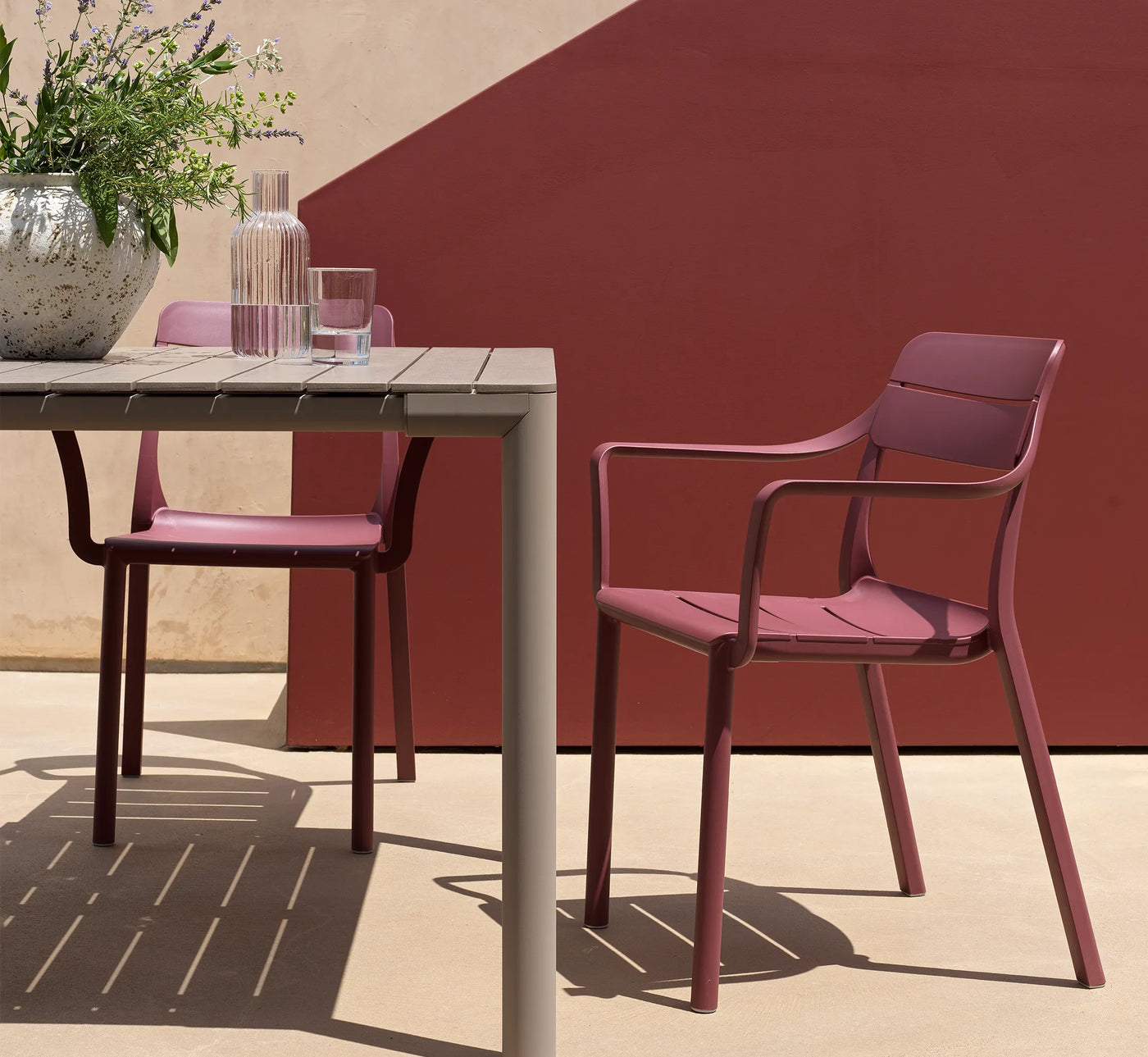 Conjunto de sillas CASSIA con brazos en una terraza.