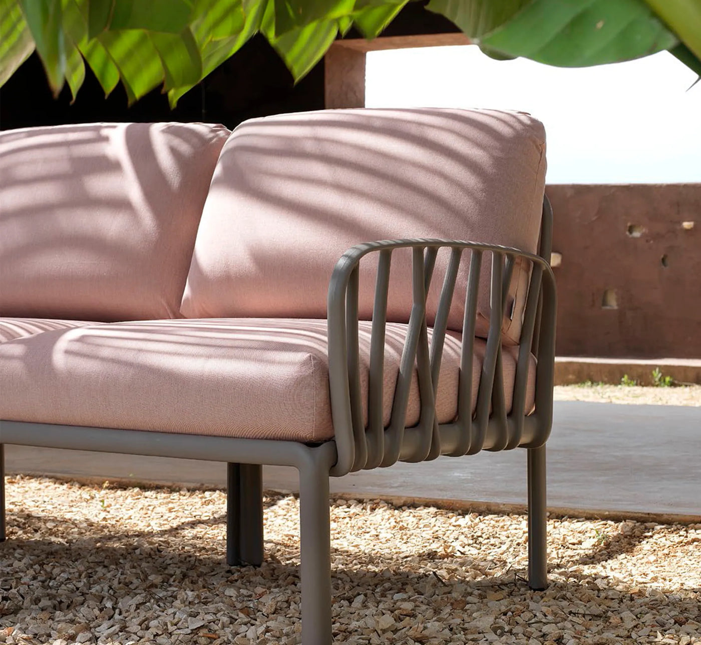 Sofá modular Komodo de Nardi configurado con elementos terminales en un proyecto de obra residencial con pavimento minimalista y vistas al jardín.