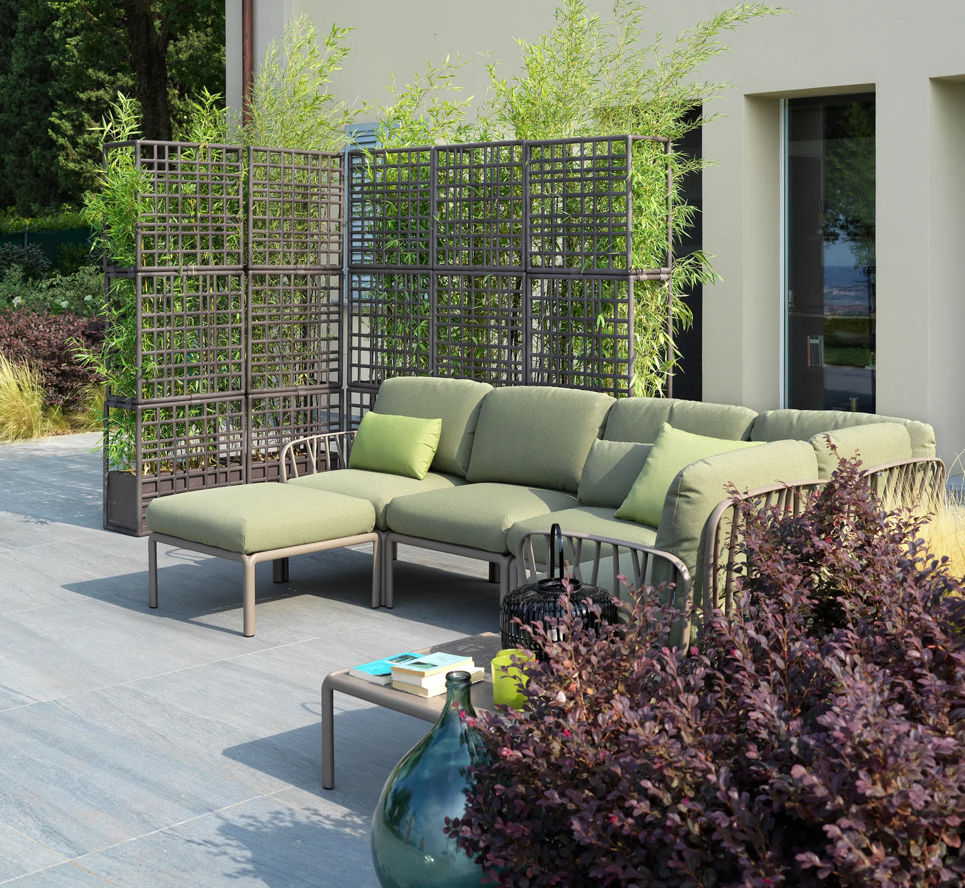 Sofá de exterior en forma de L configurado con el elemento angular Komodo, ideal para zonas de bienestar.