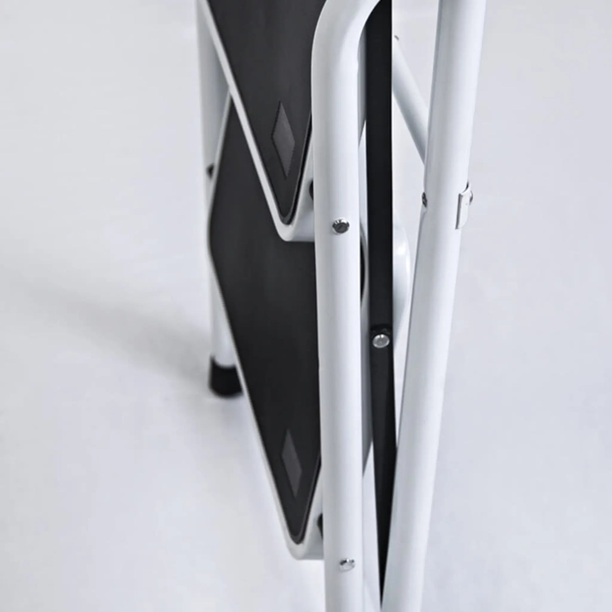 Taburete White plegado mostrando su diseño compacto para almacenamiento en espacios pequeños.